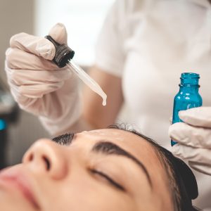 Doctor beautician applies oil to the skin of the face