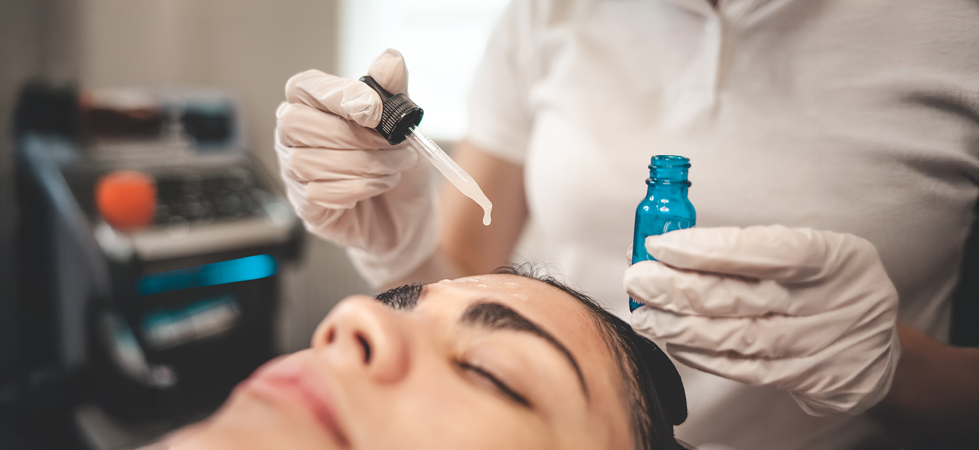 Doctor beautician applies oil to the skin of the face